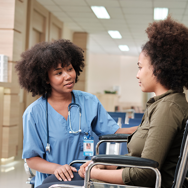 Doctor crouched down to speak to woman using a wheelchair