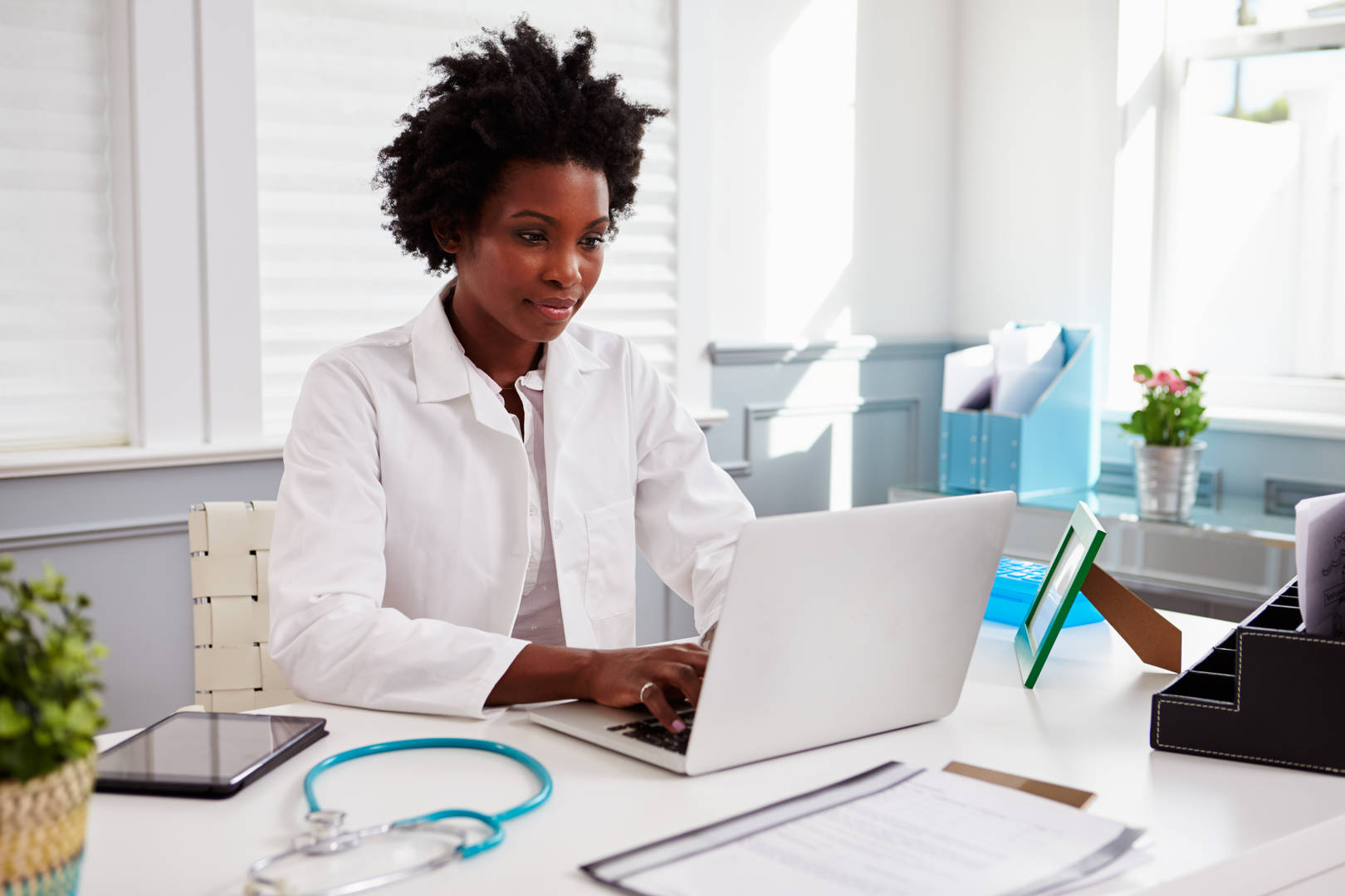 Doctor looking at a laptop, sitting at a desk